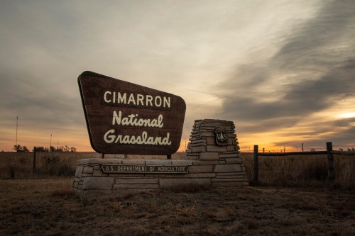Sign for Cimarron National Grassland at sunset, featuring rustic design and U.S. Department of Agriculture emblem.