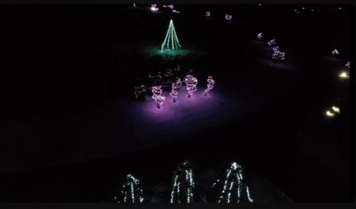 Aerial view of a festive display with colorful Christmas lights, including a green tree and illuminated figures.