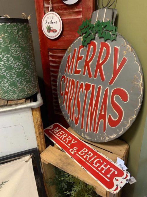 A festive display featuring a large "MERRY CHRISTMAS" sign and a smaller "MERRY & BRIGHT" sign, surrounded by holiday decor.