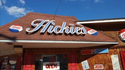 Sign for "Hickies" restaurant with a wooden exterior and blue sky in the background.