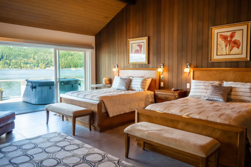 Cozy bedroom with two beds, large windows overlooking a lake, and warm wooden accents.