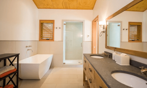 Modern bathroom featuring a freestanding tub, double sinks, and a glass shower enclosure with wooden accents.