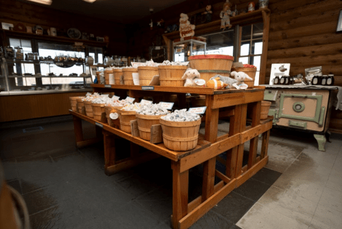 A wooden table filled with baskets of colorful candies in a rustic shop with a cozy atmosphere.