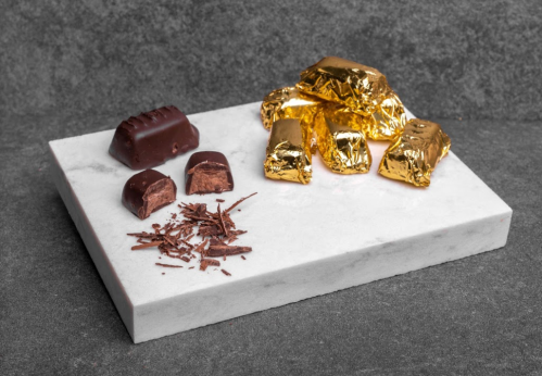 Assorted chocolates on a marble surface, including wrapped pieces and chocolate shavings.