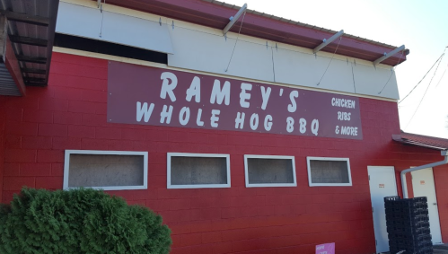 Red building exterior with a sign that reads "Ramey's Whole Hog BBQ" featuring chicken, ribs, and more.