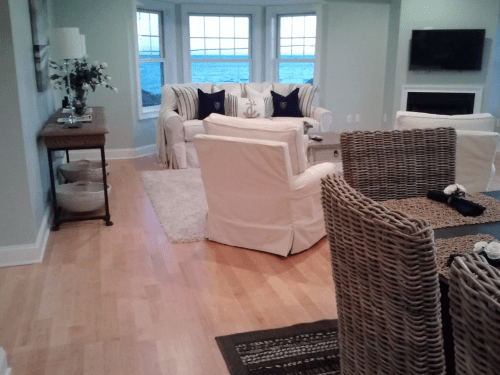 Cozy living area with white furniture, a wooden table, and large windows overlooking a scenic view.