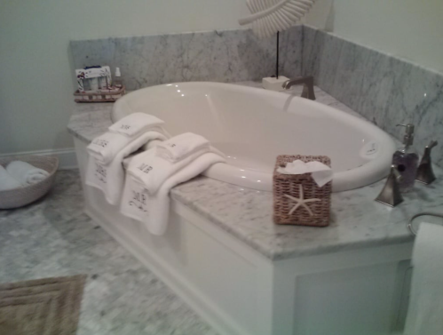 A luxurious bathroom featuring a large oval bathtub, marble surfaces, and neatly arranged towels and decor.