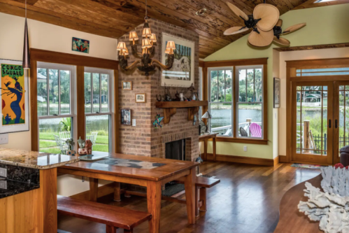 Cozy interior of a home with wooden accents, a dining table, and large windows overlooking a scenic view.
