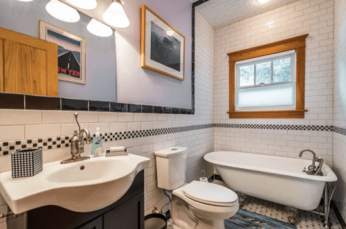 A modern bathroom featuring a freestanding tub, sink, and stylish decor with tiled walls and wooden accents.