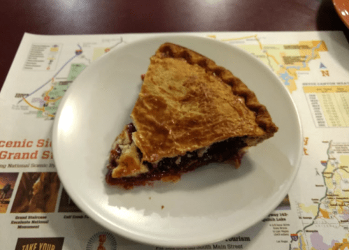 A slice of pie on a white plate, resting on a colorful map of scenic sites.