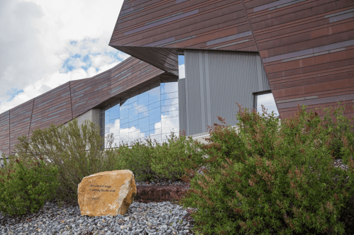 Modern building with angular design, large windows, and landscaped stone features in front.