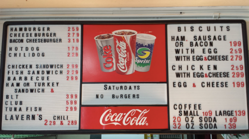 Menu board displaying food items and prices, including burgers, sandwiches, biscuits, and drinks.