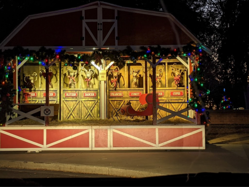A festive display featuring Santa's reindeer in a decorated booth, illuminated with colorful lights.