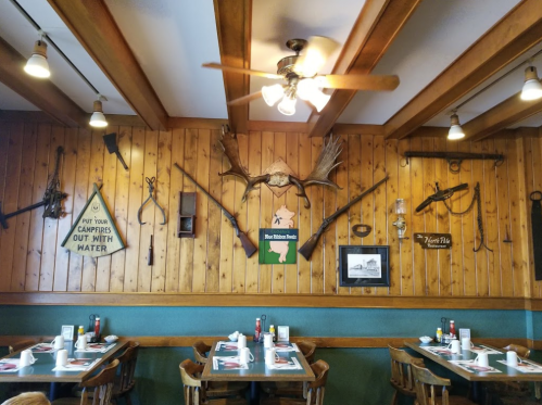 Rustic restaurant interior featuring wooden walls, vintage decor, and tables set for dining.
