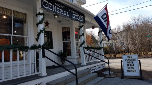 A quaint general store with festive decorations and a sign reading "Hot flashes make great snow angels."