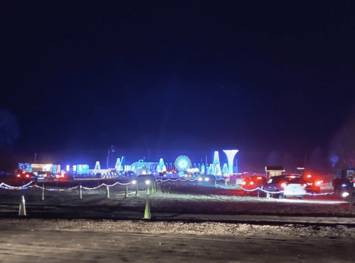 A nighttime scene of colorful lights and decorations, with cars lined up in a festive display.