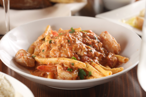 A bowl of pasta with shrimp in a creamy tomato sauce, garnished with parsley.
