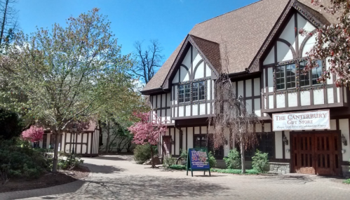 A charming Tudor-style gift store surrounded by blooming trees and a clear blue sky.