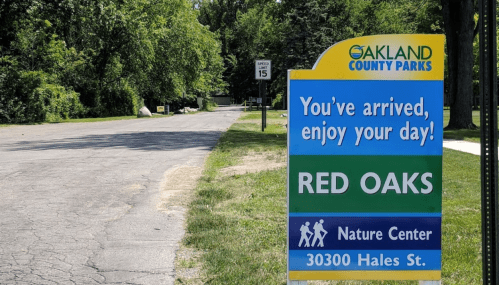 Sign for Oakland County Parks welcoming visitors to Red Oaks Nature Center, located at 30300 Hales St.