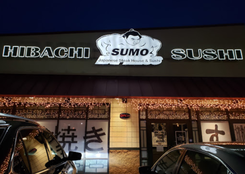 Sign for "Hibachi Sumo" Japanese Steak House & Sushi, illuminated at night with festive lights.