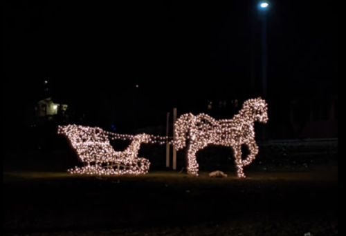 A glowing horse and sleigh made of lights, set against a dark night sky.