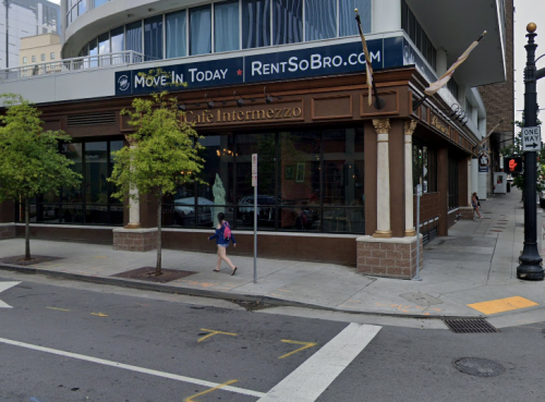 A street view of Café Intermezzo with a pedestrian walking by and a "Move In Today" sign above.