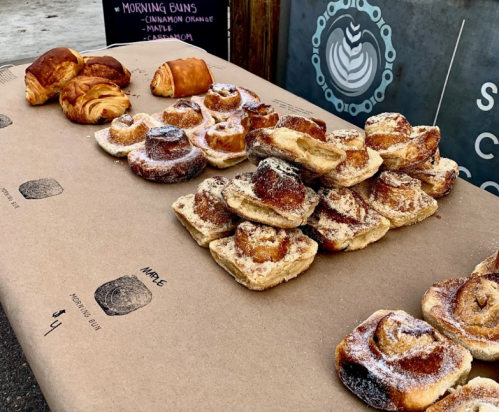 A table displaying various baked goods, including cinnamon rolls and croissants, on brown paper.
