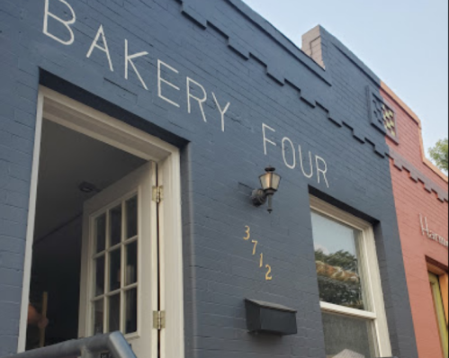 Exterior of a bakery with the sign "Bakery Four" on a blue wall, featuring a door and a light fixture.