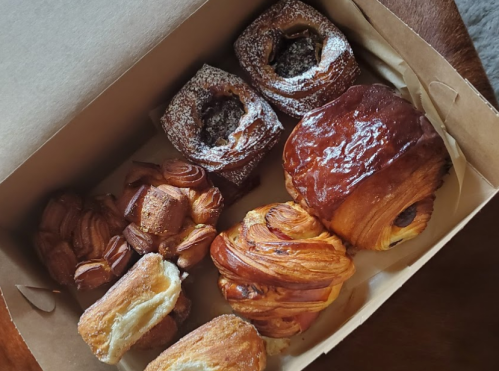 A box of assorted pastries, including croissants, danishes, and sweet rolls, arranged neatly.