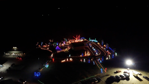 Aerial view of a festive light display at night, featuring colorful decorations and illuminated pathways.