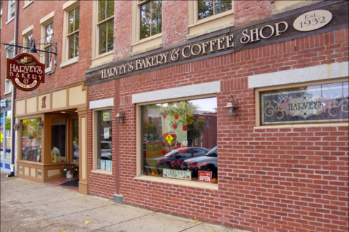 Exterior of Harvey's Bakery & Coffee Shop, featuring a brick facade and large windows with an "Open" sign. Established 1932.