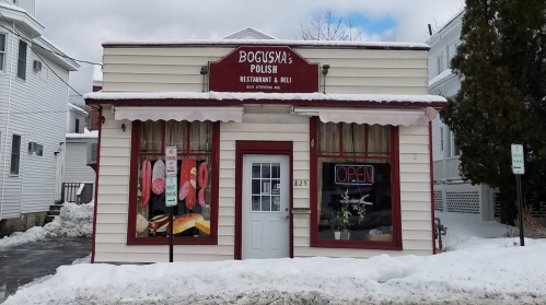 A small Polish restaurant and deli with a red sign, open for business, surrounded by snow-covered ground.