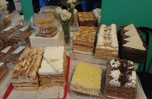 A variety of layered cakes and pastries displayed on a table, featuring different textures and toppings.