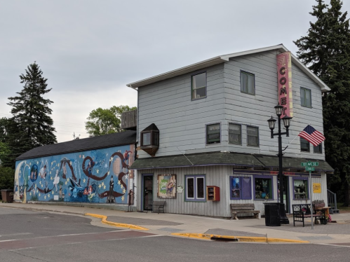 A colorful building with a mural on the side, featuring a sign that reads "Comet," located at a street corner.