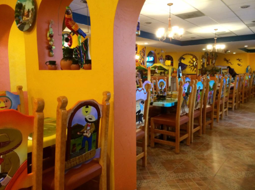 Colorful restaurant interior with vibrant chairs and decor, featuring arches and a lively atmosphere.