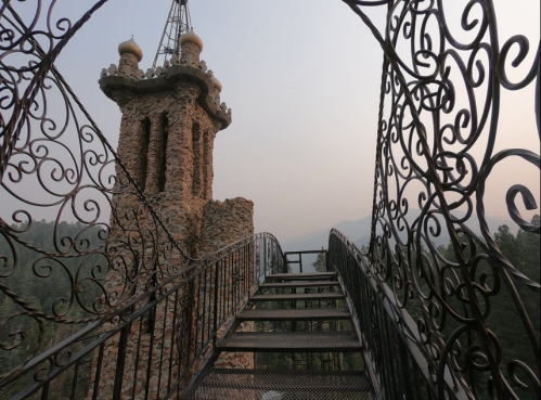 A stone tower with ornate metalwork leads to a misty landscape in the background, creating a serene atmosphere.