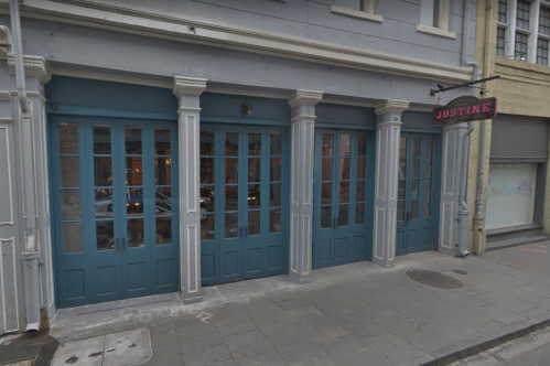 Exterior of a restaurant named "Justine," featuring large blue doors and windows, with a stylish urban setting.