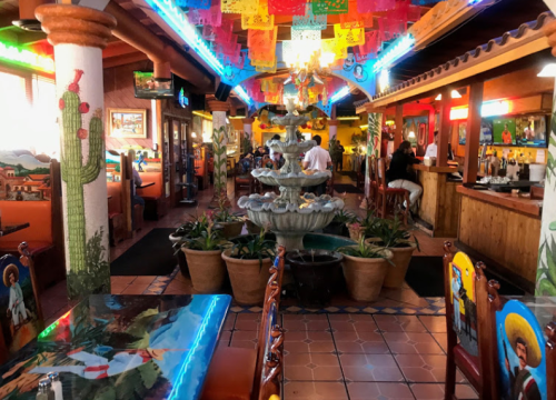 Colorful restaurant interior featuring a fountain, vibrant decorations, and a lively atmosphere.