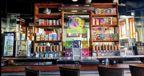 Colorful cereal-themed café bar with shelves of cereal boxes, drinks, and a vibrant sign welcoming guests.