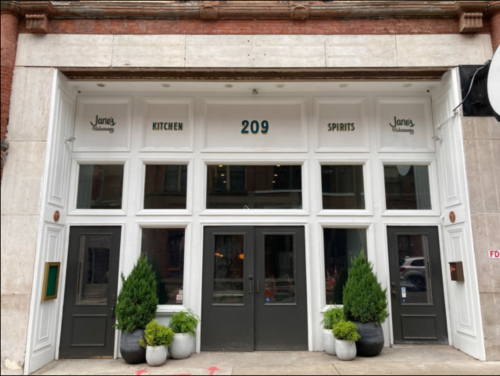Exterior of a restaurant with large windows, featuring the name "Jane's" and the words "Kitchen" and "Spirits" above the entrance.
