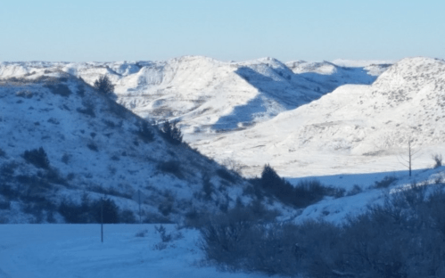 Snow-covered hills under a clear blue sky, showcasing a serene winter landscape.