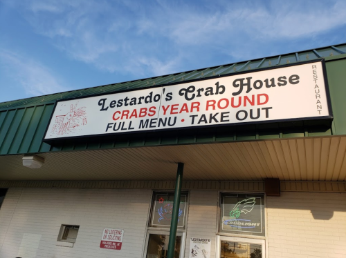 Sign for Lestardo's Crab House, featuring "Crabs Year Round" and "Full Menu • Take Out" on a green building.