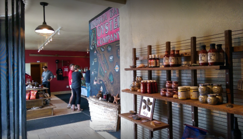 Interior of a store featuring shelves of products, a colorful wall mural, and customers browsing.