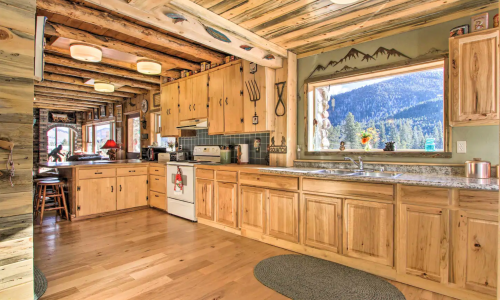 Cozy kitchen with wooden cabinets, granite countertops, and a large window showcasing a mountain view.