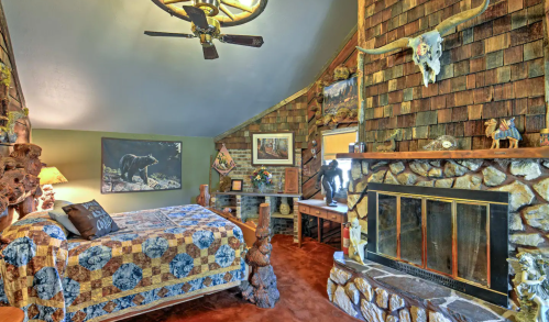 Cozy rustic bedroom with a stone fireplace, wooden decor, and wildlife-themed artwork.