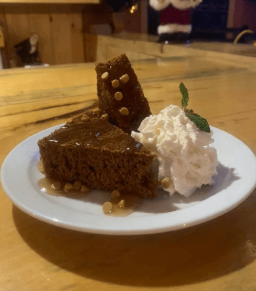 A plate with two pieces of chocolate cake topped with chocolate chips, whipped cream, and a mint leaf.