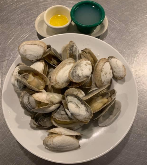 A plate of clams with two dipping sauces in small bowls on the side.
