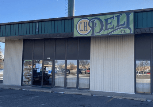 Exterior of C.H. Deli, featuring a green and yellow sign, with large windows and a parking lot in front.