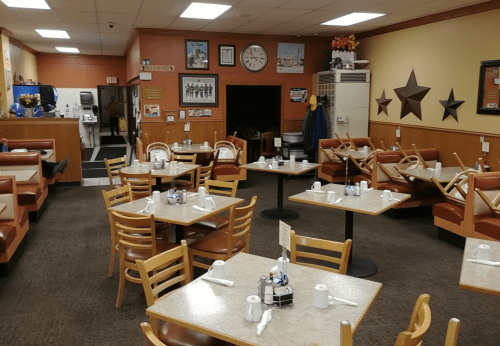A cozy diner interior with empty tables, booths, and decor featuring stars and vintage photos on the walls.