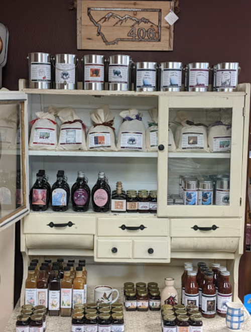 A display cabinet filled with various jars and containers of food products, including syrups and sauces.